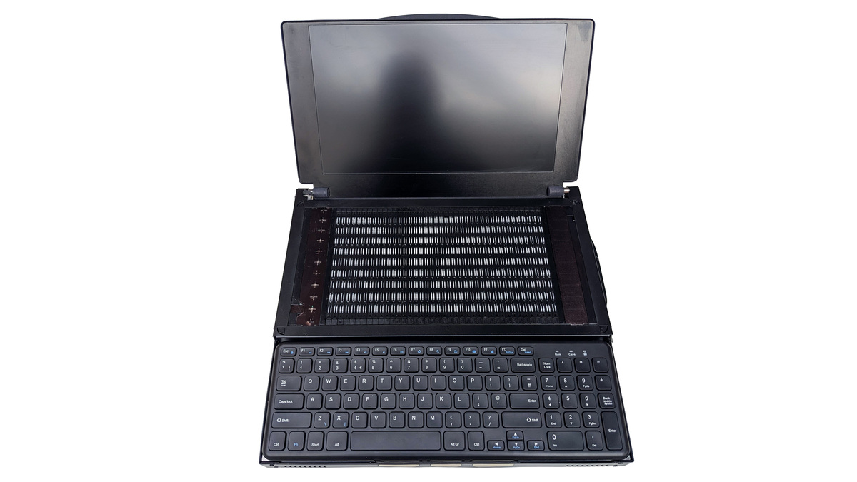 Front on photo of the Canute Scientific when open. A full size keyboard in the front with a 360 cell Braille cell behind it. There is an open lid at the back with a 13" visual monitor. The device is black with white details.