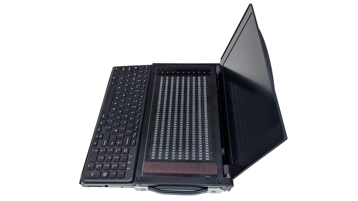 Side on photo the Canute Scientific when open. A full size keyboard in the front with a 360 cell Braille cell behind it. There is an open lid at the back with a 13" visual monitor. There is a heavy duty pull-out handle on the right side. The device is black with white details.