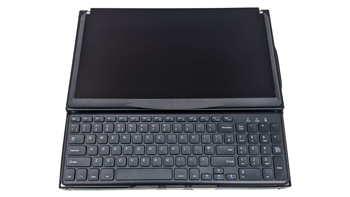 Top down photo of the left side Canute Scientific when closed. A full size keyboard in the front. Behind this the lid is closed over the Braille display.